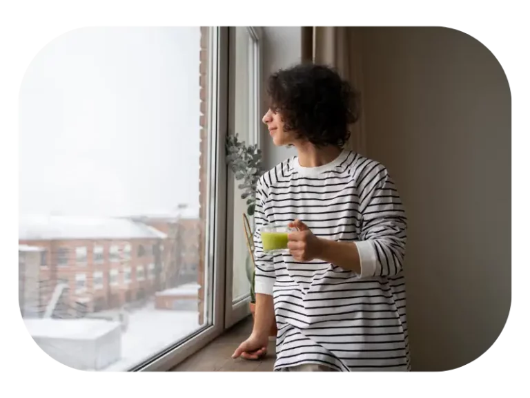 cloudy day man looking out window with macha tea natural lighting