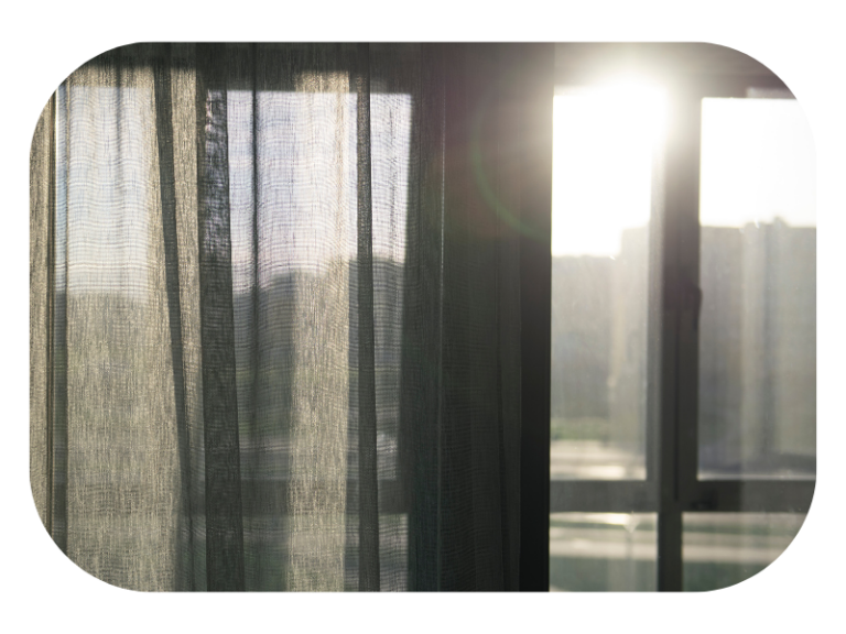 white sheer curtain over one half of window with mid morning sun